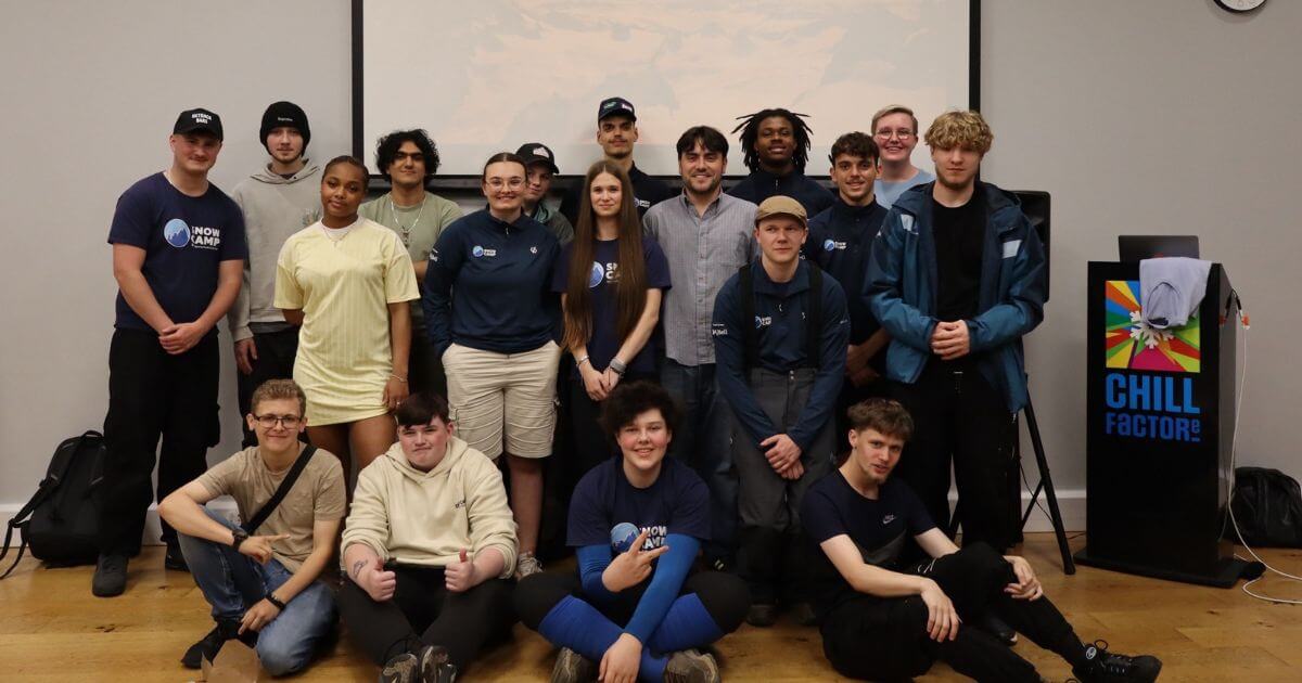 A large group of young people and mentors pose for a photo indoors at Chill Factore, many wearing Snow Camp shirts, celebrating their involvement in the SZN project to help young people gain skills and experience in snowsports.